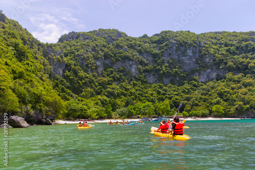 Group of tourist kayaking in the ocean sea explore near the island with lush green jungle trees and lime stone mountains in Ang Thong National Marine Park,Surat Thani, South of Thailand