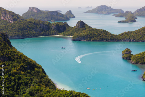 View from the viewpoint deck in Koh Wua Ta Lap, boat floating and running on blue turquoise ocean and group of islands in Ang Thong National Marine Park in the Gulf of Thailand. Surat Thani, Thailand 