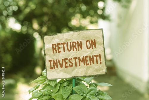 Writing note showing Return On Investment. Business concept for perforanalysisce measure used evaluate efficiency of investment Plain paper attached to stick and placed in the grassy land © Artur