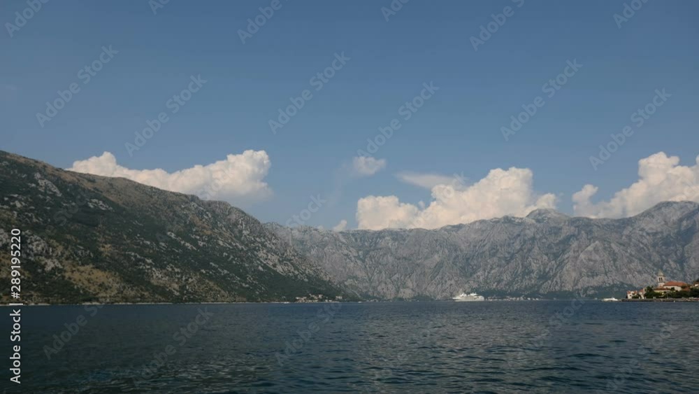 Time lapse of beautiful clouds over the hill in a bay on a sunny day with vessels passing by Time lapse of beautiful clouds over the hill in a bay on a sunny day with vessels passing by