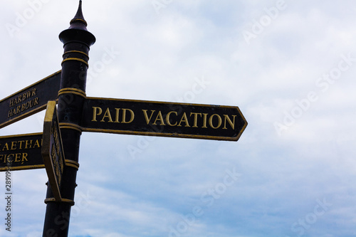 Text sign showing Paid Vacation. Business photo text Sabbatical Weekend Off Holiday Time Off Benefits Road sign on the crossroads with blue cloudy sky in the background