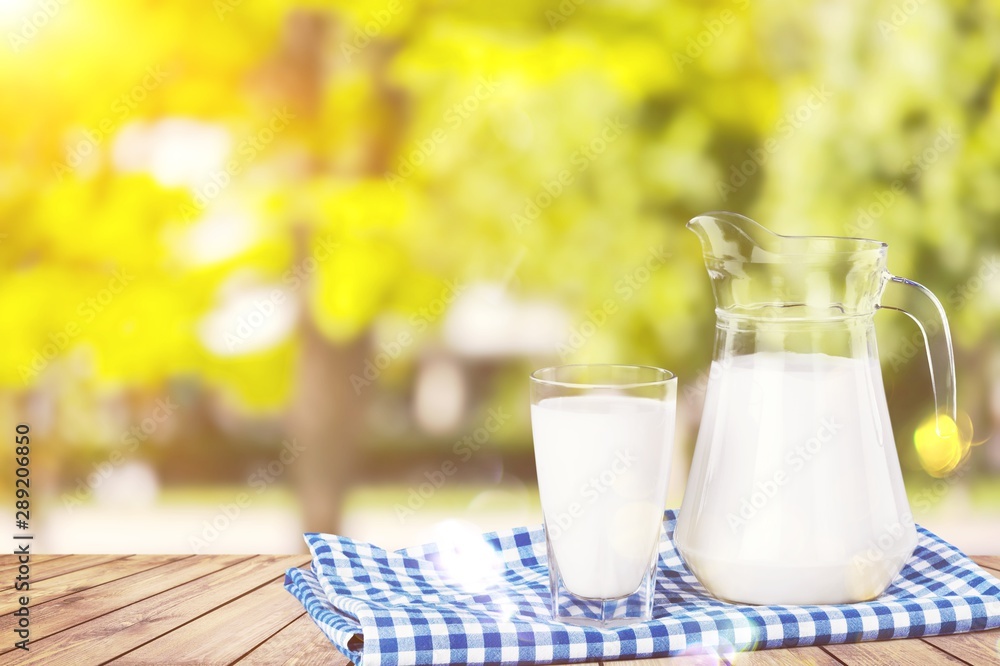 Glass of milk and jug on blurred background Glass of milk and jug on blurred background