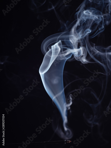 Abstract white smoke isolated on black background, close up view. Incense stick smouldering with white smoke, abstract background, brush effect. Aromatic stick for meditation and relaxation