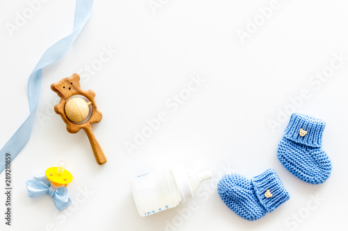Obraz na plátne Blue knitted footwear for kids, dummy, rattle and bottle on white background top