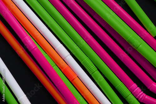 Plastic straws different colors on a dark background close up