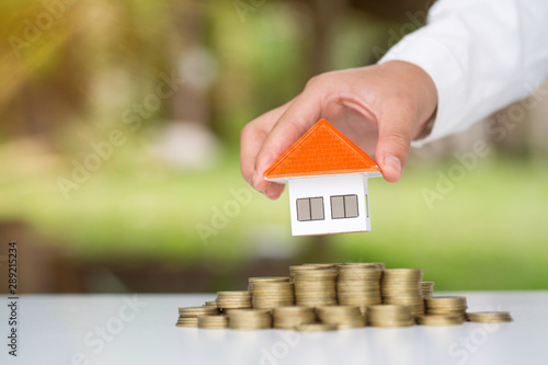 Orange roof house Held by investors Will put on a pile of coins.Concept of planning for saving money to buy a house, mortgage concept and investment Saving or investing for the house.
