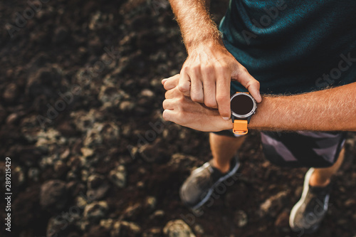 Fototapeta Naklejka Na Ścianę i Meble -  Young athletic man using fitness tracker or smart watch before run training outdoors. Close-up photo with dark background.