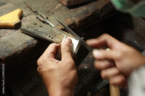hands and tools of a professional silversmith working on a piece in his traditional workshop, Northern Thailand photo