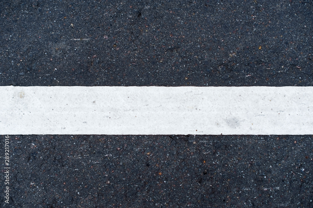 Fototapeta premium white horizontal road marking line on asphalt in the center of the image close up