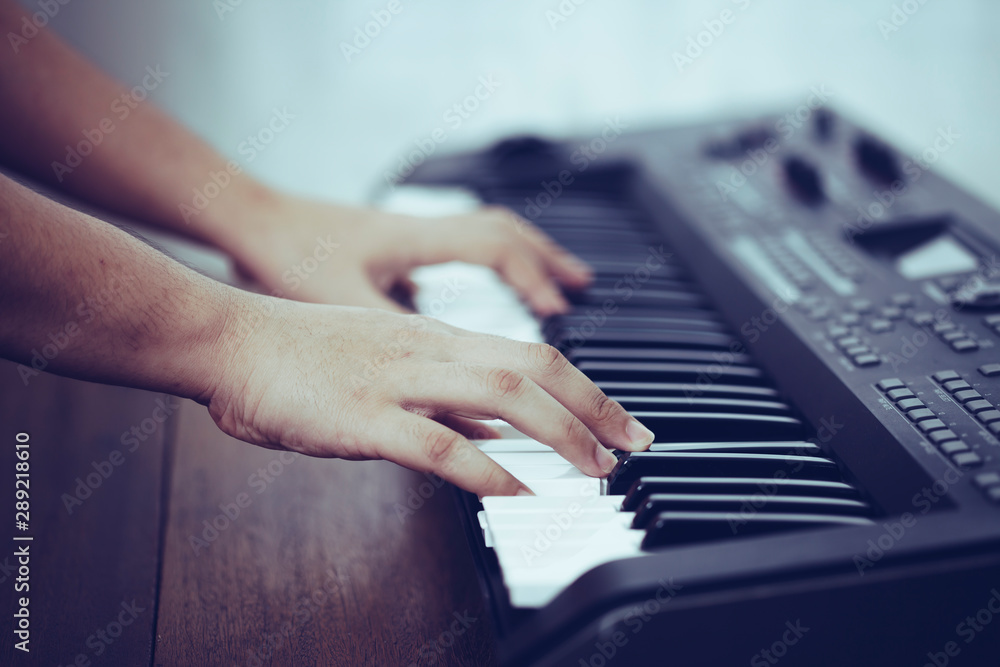 Obraz premium close up of man hands is playing on piano keys with window light