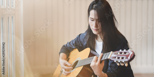 Attractive woman holding acoustic guitar in her free time at home