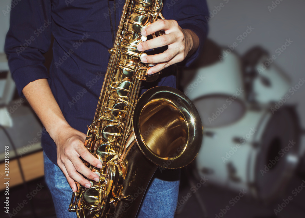 Naklejka premium a musician plays tenor saxophone on stage with blurred music instrument background