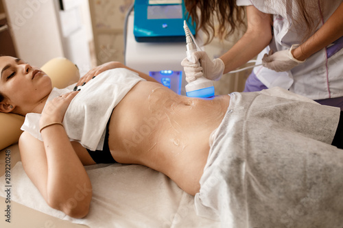 Hardware cosmetology. Body care. Spa treatment. Ultrasound cavitation body contouring treatment. Woman getting anti-cellulite and anti-fat therapy in beauty salon. photo