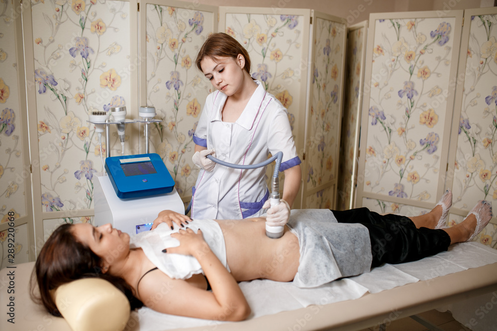 Vacuum massage device. Anti cellulite body correction treatment. Loss weight apparatus. Woman and doctor at medicine salon. Beauty saloon. vacuum massage of the abdomen. Anticellulite massage Vacuum massage device. Anti cellulite body correction treatment. Loss weight apparatus. Woman and doctor at medicine salon. Beauty saloon. vacuum massage of the abdomen. Anticellulite massage