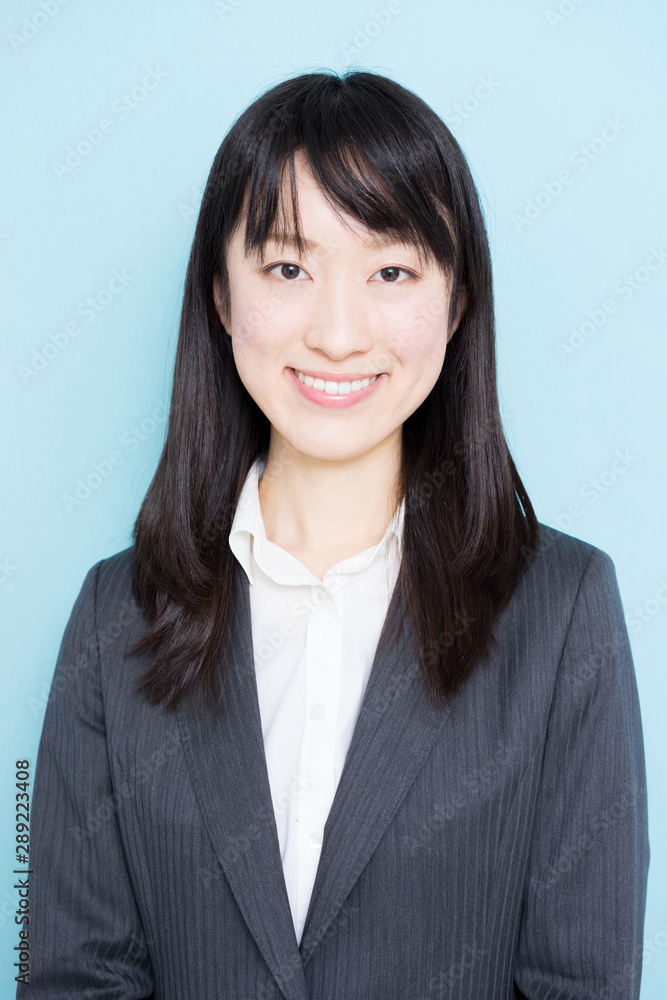 Young business woman wearing grey suit against light blue background Young business woman wearing grey suit against light blue background