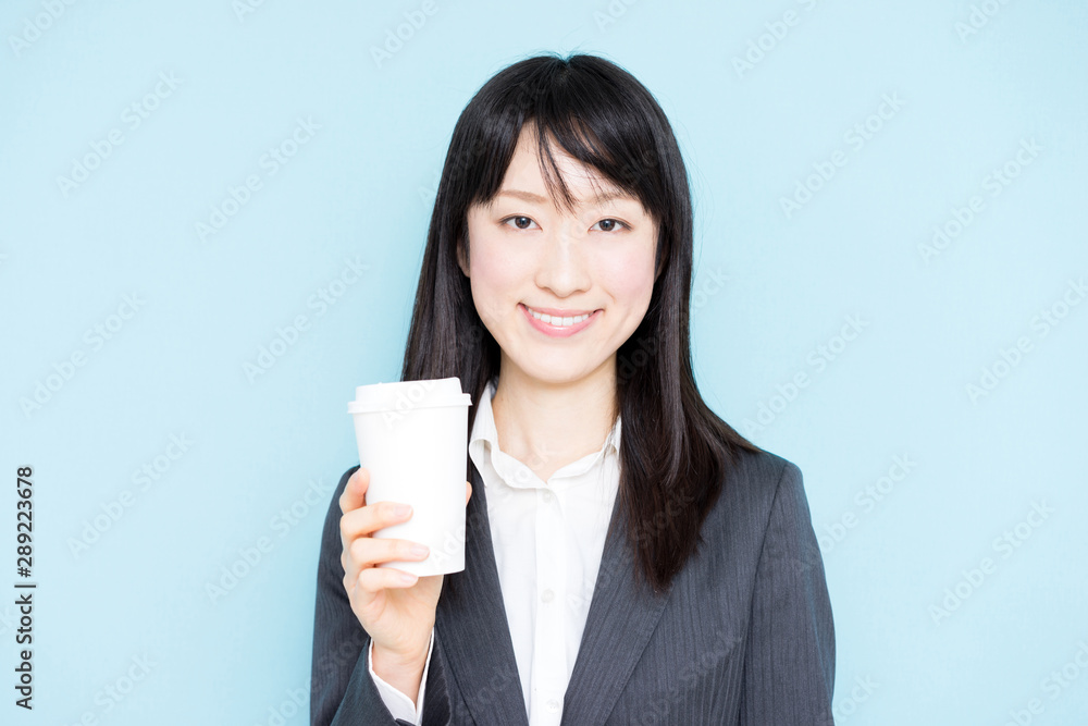 Young business woman holding coffee against light blue background Young business woman holding coffee against light blue background