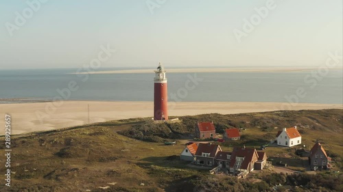Aerial shot of the beautiful lighthouse revealing wide sand beach at the Texel island (part of Wadden islands) in The Netherlands, with Vlieland island visible in the background photo
