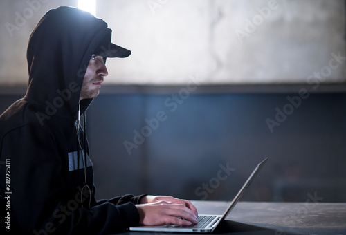 talented hacker using laptop computer while working in dark office