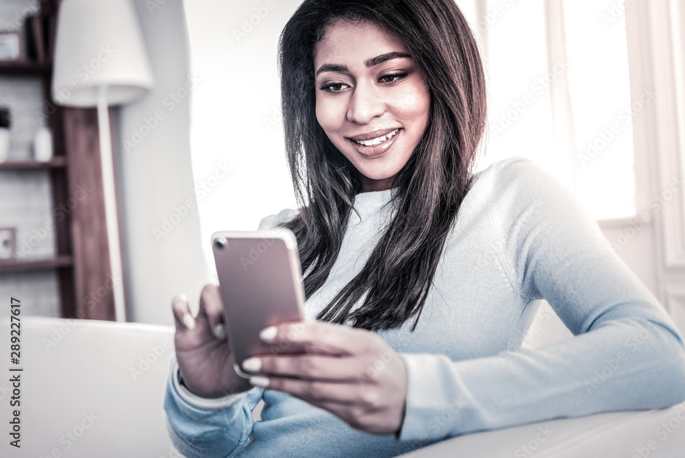 Beaming young girl looking on the screen of her smartphone Beaming young girl looking on the screen of her smartphone