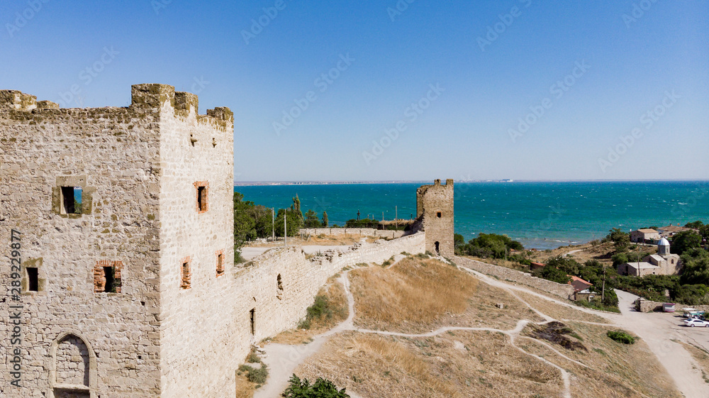 Architectural landmark, sight Of Crimea. Genoese fortress in Sudak. Aerial view of the ruins of an ancient castle or fortress on a mountain by the sea. Beautiful summer tourist landscape 