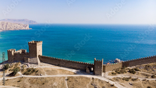 Architectural landmark  sight Of Crimea. Genoese fortress in Sudak. Aerial view of the ruins of an ancient castle or fortress on a mountain by the sea. Beautiful summer tourist landscape 