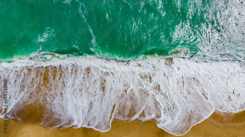 Top view of the beautiful sandy beach with turquoise sea water. Aerial drone shot at the big ocean waves on the West coast. a deserted beach for travel and recreation