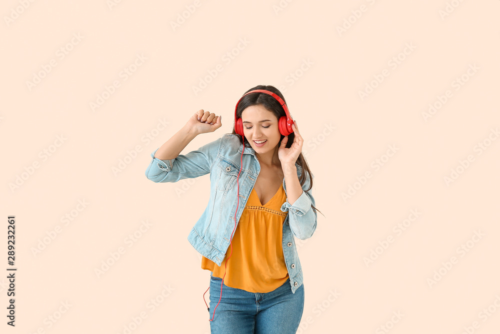 Obraz premium Young woman with headphones dancing against light background