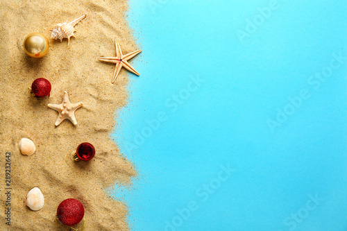 Canvas Print Beach sand with Christmas balls on color background
