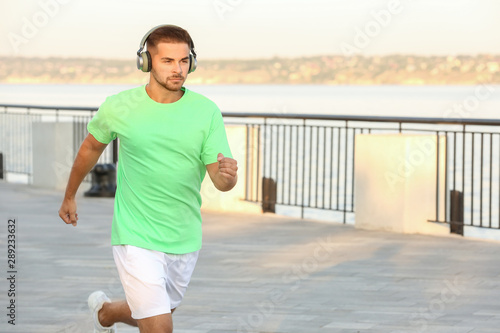 Handsome sporty man listening to music and running outdoors