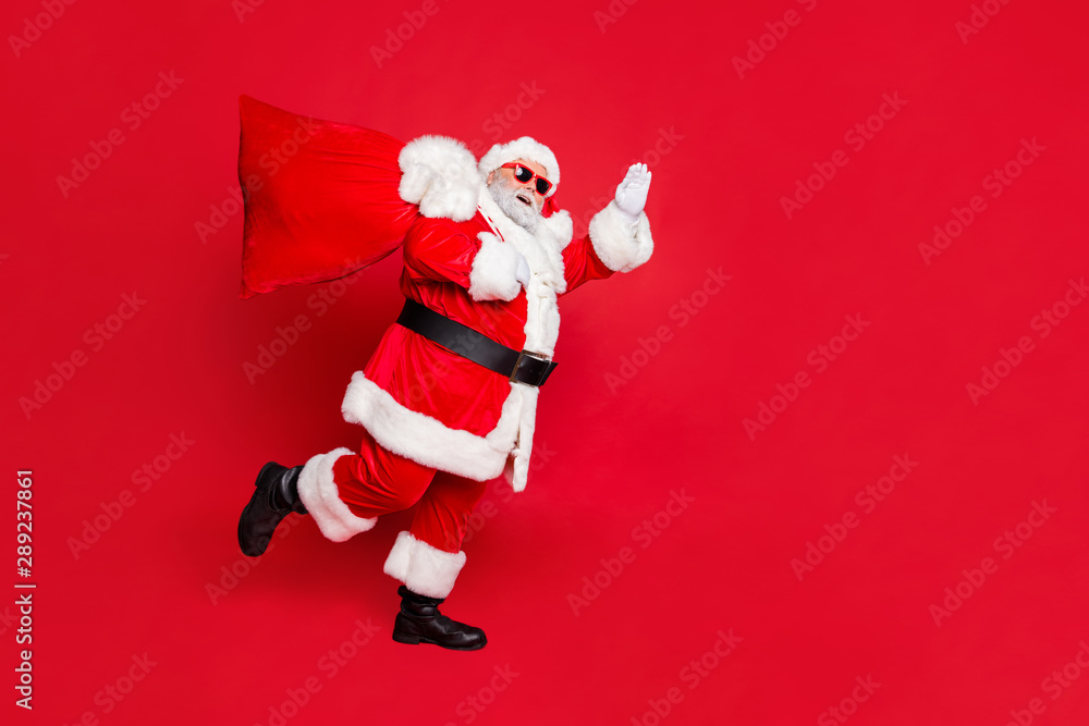 Full length body size view of cheerful cheery dreamy glad funky fat overweight plump gray-haired bearded man piggy backing gifts fairy waving greetings isolated over bright vivid shine red background Full length body size view of cheerful cheery dreamy glad funky fat overweight plump gray-haired bearded man piggy backing gifts fairy waving greetings isolated over bright vivid shine red background