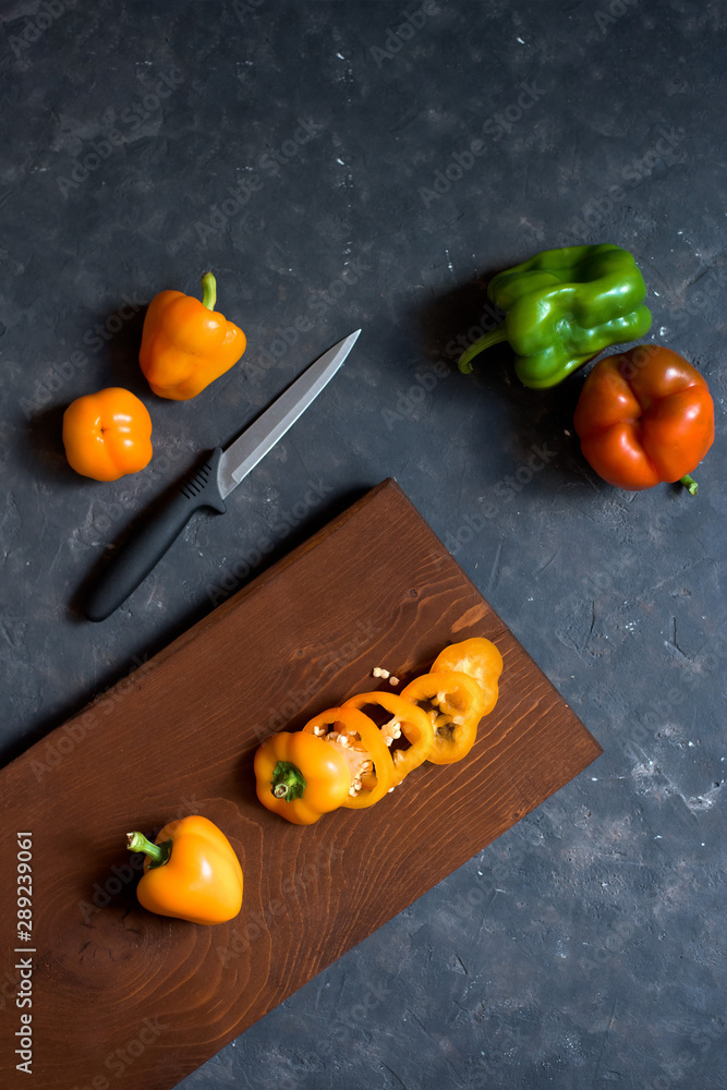 composition of fresh vegetables-cut peppers on a Board on a dark background. top view . vertical image