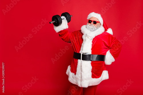 Portrait of his he nice attractive fat overweighed bearded Santa working out barbell physical exercise workout calories diet regime isolated over bright vivid shine red background