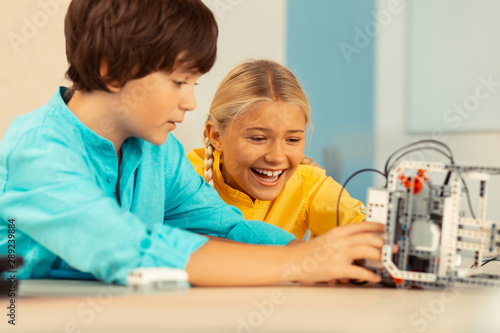 Schoolchildren being happy playing with a robot.