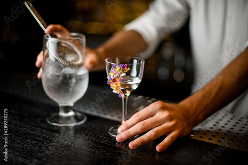 Bartender pours alcohol from glass with a strainer