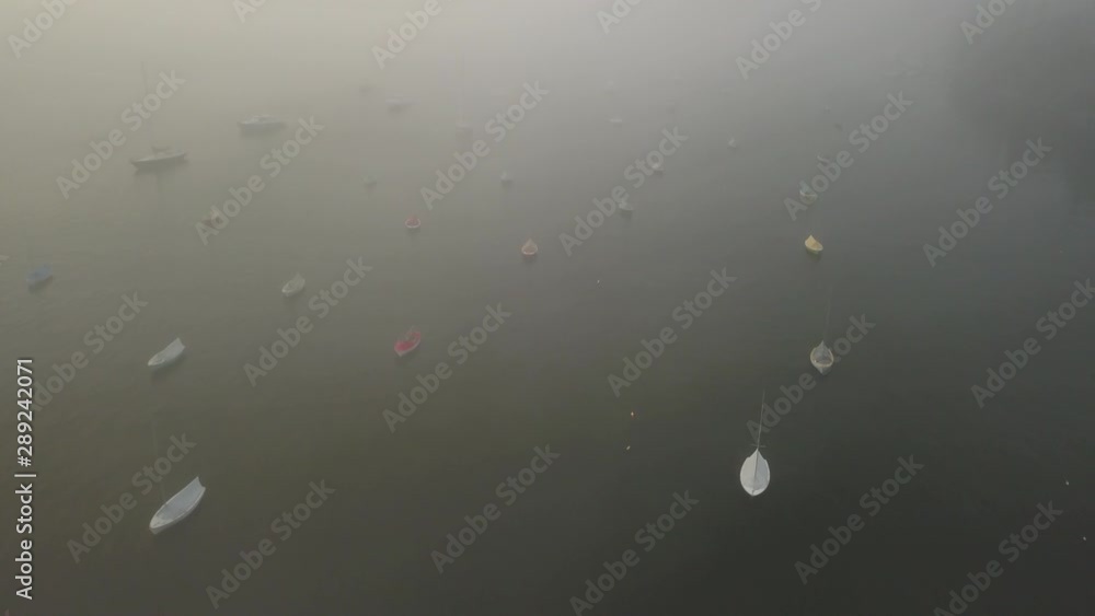 Drone flying over boats anchored in a cove on a moody and foggy morning Drone flying over boats anchored in a cove on a moody and foggy morning