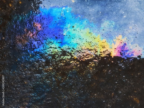 Pattern of Oily Rainbow stains on the cement. road.abstract background. Image caused by inattention