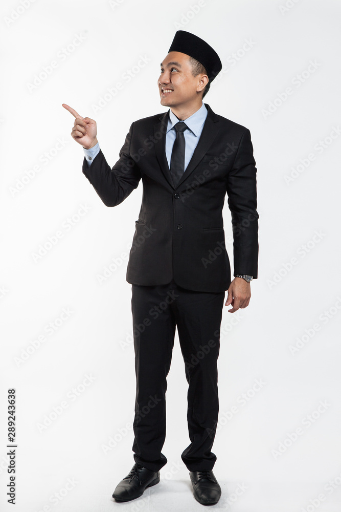 Asian business man in suit and songkok pointing his hands Asian business man in suit and songkok pointing his hands