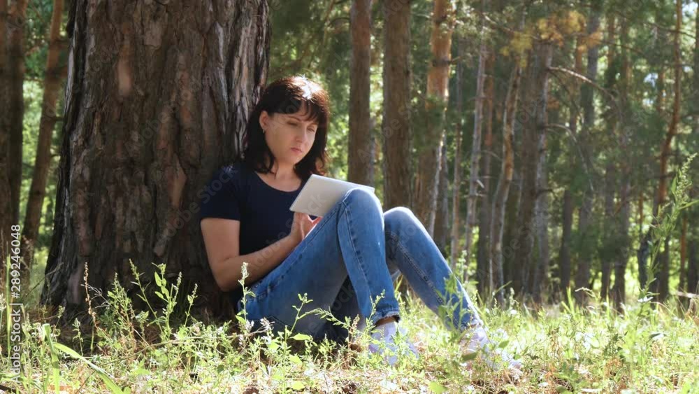 Girl freelancer works via the Internet using a tablet, sitting in the Park. Internet and technology. Girl freelancer works via the Internet using a tablet, sitting in the Park. Internet and technology.