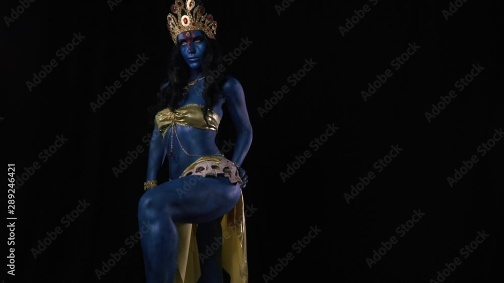 Kali is standing on black background and posing, wearing skulls on the belt Kali is standing on black background and posing, wearing skulls on the belt
