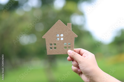 Finance and Banking concept,Woman hand holding model house on natural green background