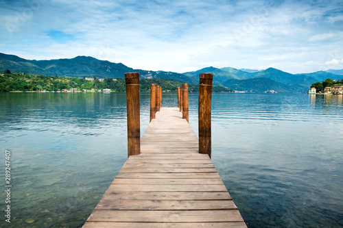 Wooden pier on Orta San Giulio Lake with mountain scenery background. Italy.