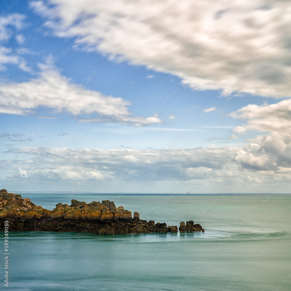 rocky cliff outcrop in a calm ocean under an expressive sky on the Emerald Coast in France