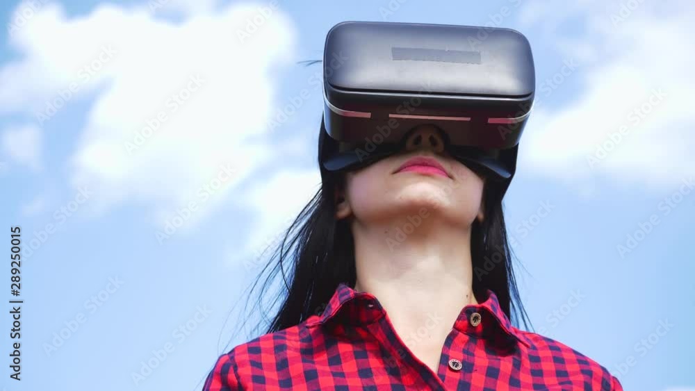A young woman in the fresh air is in virtual glasses, with interest turns his head. Virtual reality helmet, technology of the future. A young woman in the fresh air is in virtual glasses, with interest turns his head. Virtual reality helmet, technology of the future.