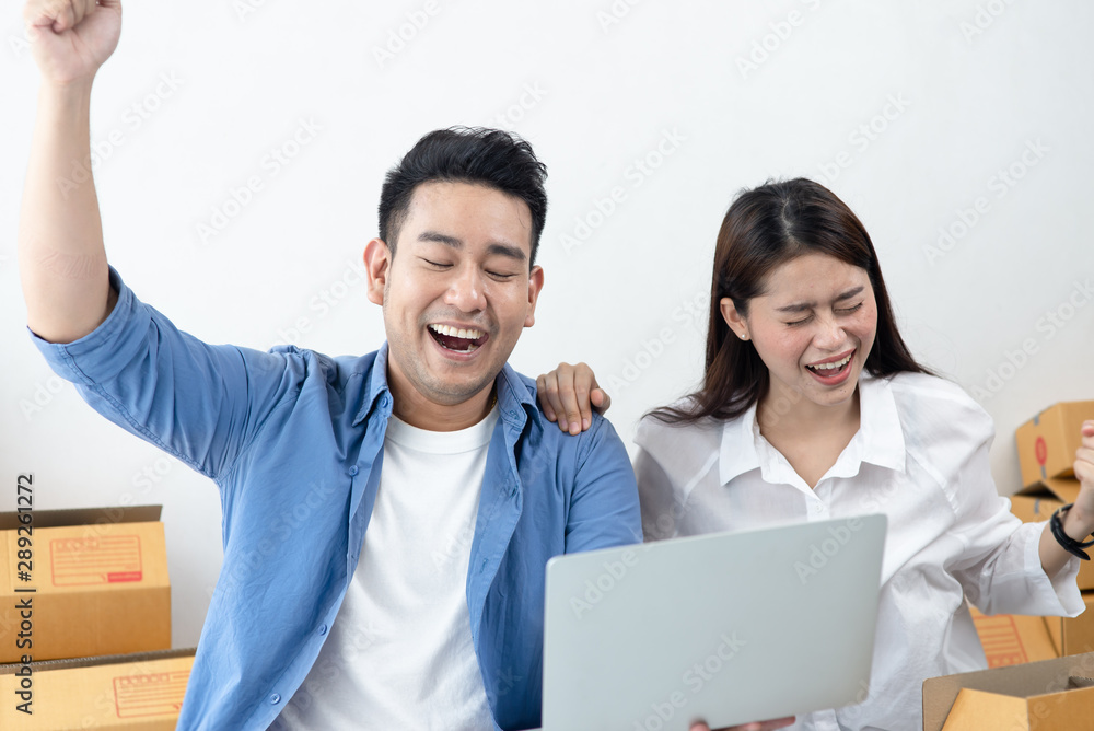 Asian couple raising hands with brown boxes parcel background. Asian couple raising hands with brown boxes parcel background.