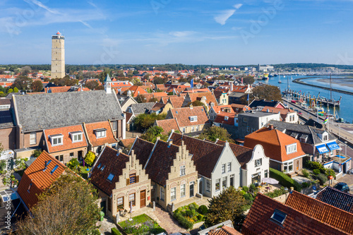 Netherlands, Terschelling - Aug 25, 2019: Brandaris lighthouse and Westerkerk, harbour and historical houses of West-Terschelling town. Shallow waters, sandy banks in low tide. West Frisian Islands photo
