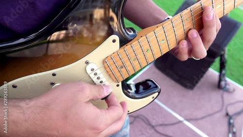 Strumming Electric Guitar. This stock footage features a close-up of a man on stage as he strums his electric guitar with a pelctrum.