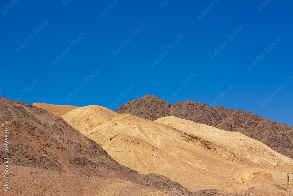 Israel desert yellow and brown sand stone rocky hills simple scenery landscape photography with empty blue sky background 