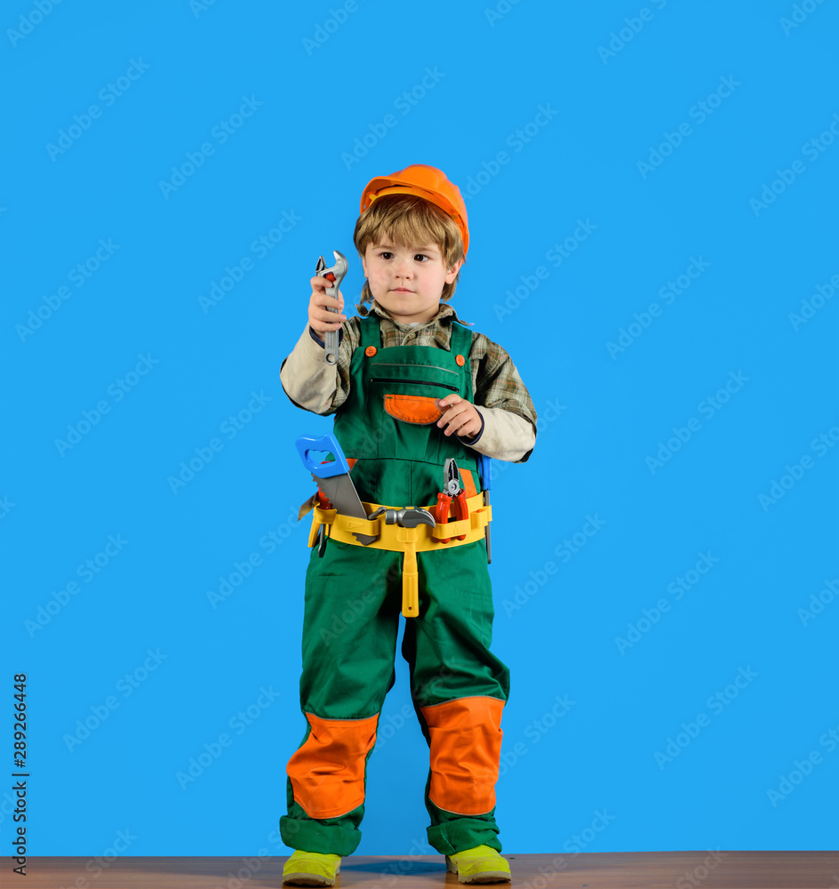 Little kid boy in builder uniform with wrench. Tools for building. Kid repairman with tool belt. Work with tools. Repair. Kid boy as builder or repairer. Builder boy in helmet and tools. Child game. Little kid boy in builder uniform with wrench. Tools for building. Kid repairman with tool belt. Work with tools. Repair. Kid boy as builder or repairer. Builder boy in helmet and tools. Child game.