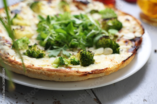 Vegetarian pizza with broccoli, garlic sauce, vegan mozzarella cheese and almonds