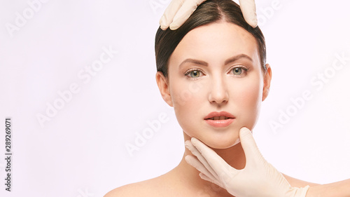 Female derma rejuvenate treatment. Doctor in gloves touch woman face. Cosmetology pretty portrait. Facial injection patient photo